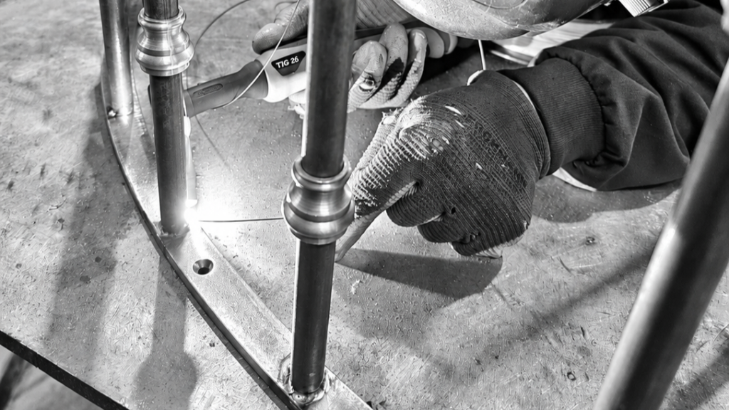 Artisan métallier réalisant la soudure d'un garde-corps en acier sur mesure, reproduit à l'identique de l'existant dans notre atelier en Mayenne.