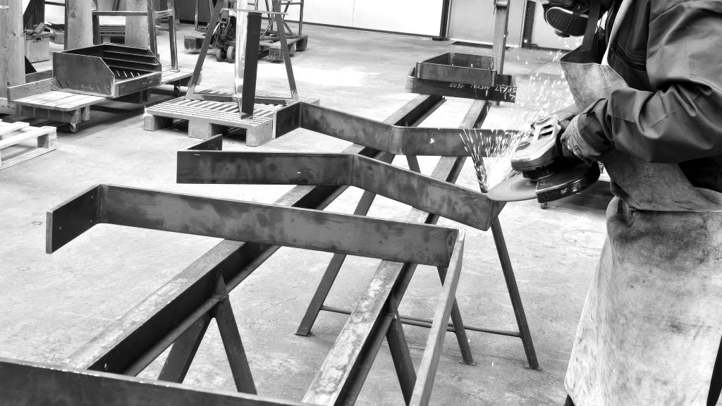 Maxime réalisant le meulage de pieds de table métalliques sur mesure dans l'atelier Esprit Métal en Mayenne.