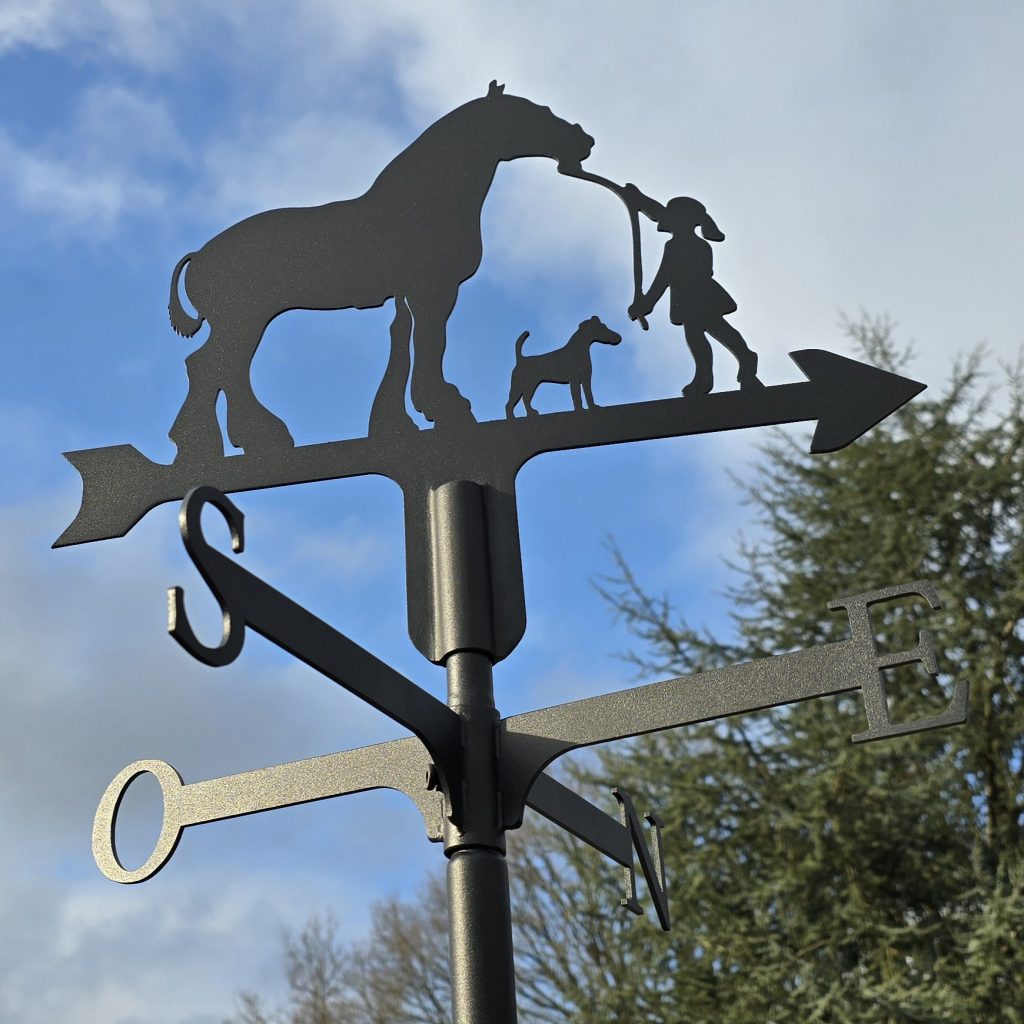 Girouette artisanale en métal noir représentant un cheval, un chien et un personnage, avec points cardinaux