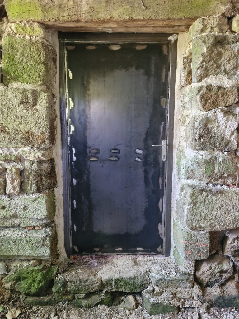 Porte métallique extérieure en acier brut avec serrure, fabriquée sur mesure par Esprit Métal en Mayenne.